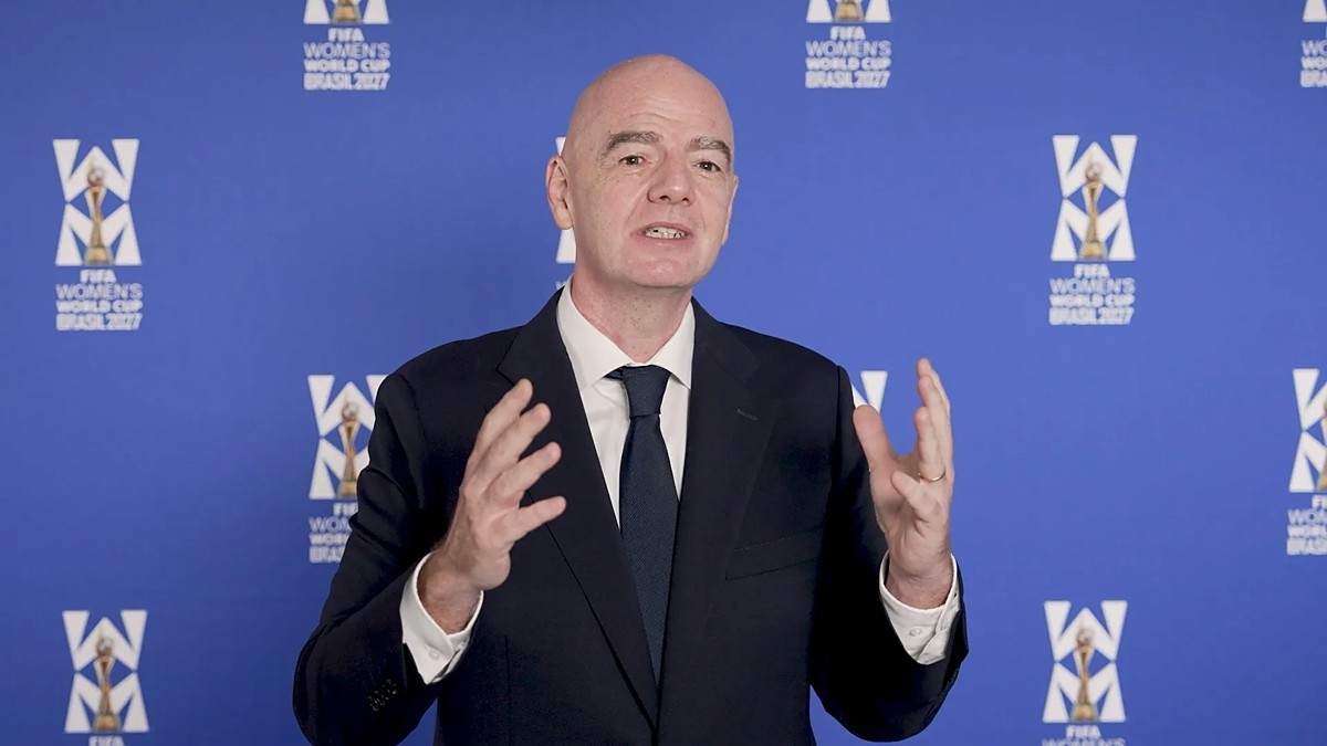 FIFA president Gianni Infantino gestures with both hands while speaking in front of a FIFA Women's World Cup backdrop.