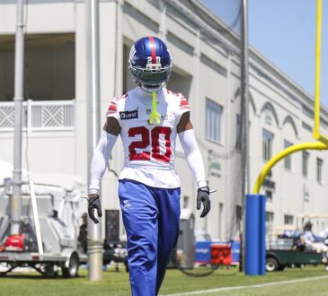 New York Giants cornerback Greg Newsome II, No. 20, walks the sideline in helmet and practice jersey at camp.