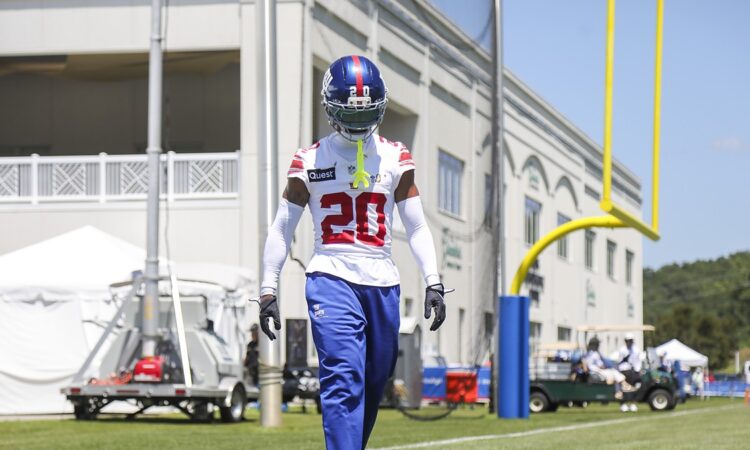 New York Giants cornerback Greg Newsome II, No. 20, walks the sideline in helmet and practice jersey at camp.