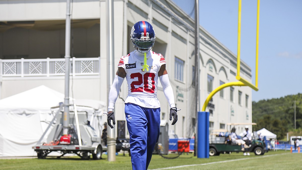 New York Giants cornerback Greg Newsome II, No. 20, walks the sideline in helmet and practice jersey at camp.