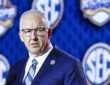 SEC Commissioner Greg Sankey speaks at a podium in front of a wall of conference logos.