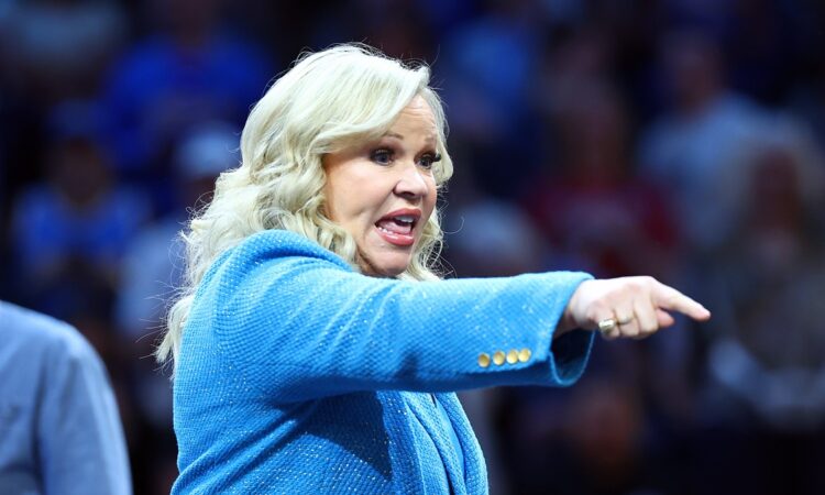 A woman in a blue blazer points toward the court during the women's national championship game.