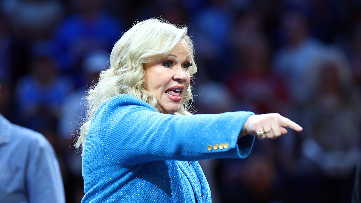 A woman in a blue blazer points toward the court during the women's national championship game.