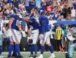 New York Giants players celebrate a touchdown in the end zone as two Dallas Cowboys defenders walk away.