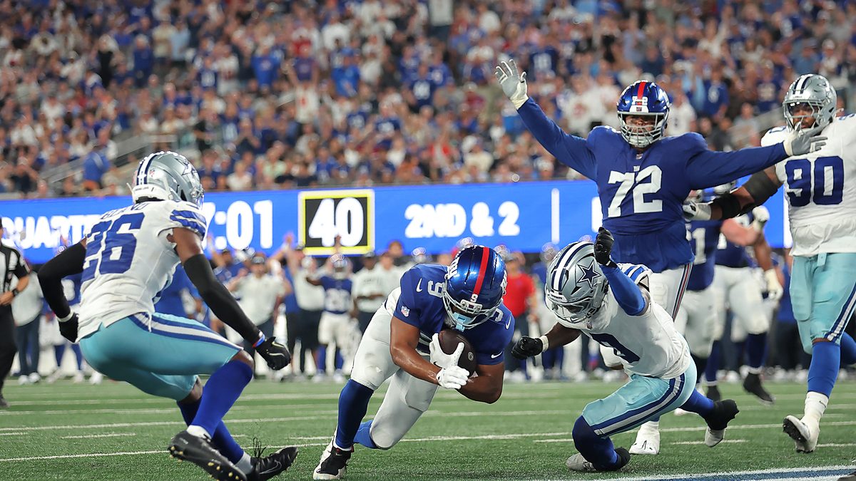 New York Giants tight end Isaiah Likely dives across the goal line as two Dallas Cowboys defenders close in.