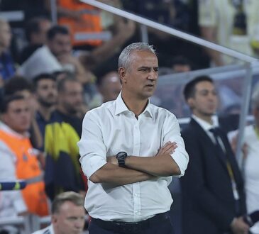 Fenerbahçe head coach İsmail Kartal stands with his arms folded on the touchline watching the match.