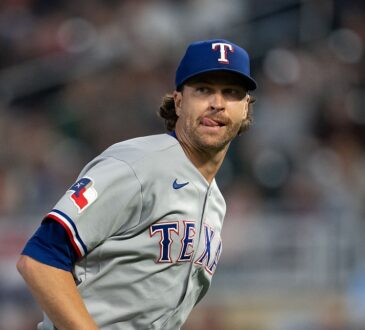 Texas Rangers starting pitcher Jacob deGrom glances to the side with his tongue at the corner of his mouth.