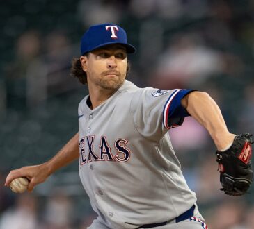 Texas Rangers starting pitcher Jacob deGrom winds up to throw a pitch in a gray road uniform and blue cap.