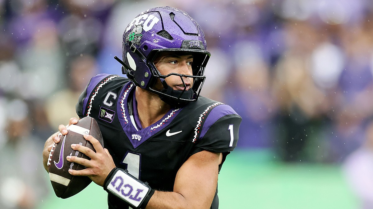 TCU quarterback Jaden Craig holds the ball at his chest and scans downfield during a rainy game.