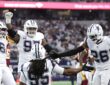 Cowboys linebacker Jaishawn Barham kneels as teammates Donovan Ezeiruaku, Kenny Clark, and DaRon Bland celebrate around him.