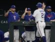 Texas Rangers first baseman Jake Burger, No. 21, reaches for a high-five at the dugout rail after scoring.