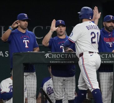 Texas Rangers first baseman Jake Burger, No. 21, reaches for a high-five at the dugout rail after scoring.