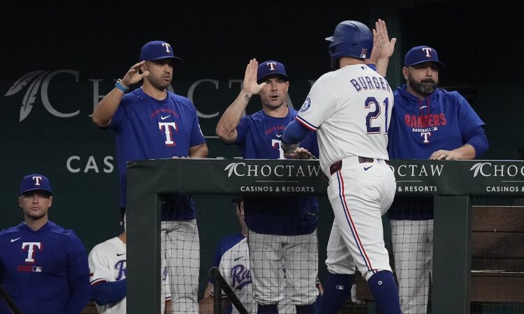 Texas Rangers first baseman Jake Burger, No. 21, reaches for a high-five at the dugout rail after scoring.