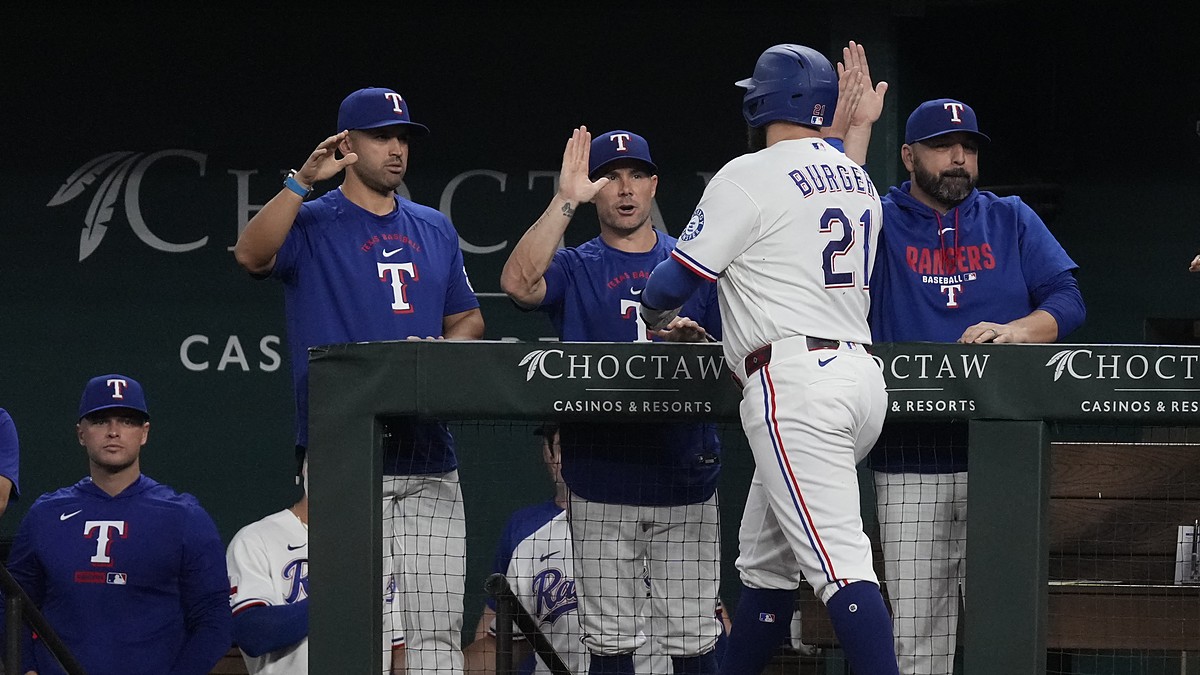 Texas Rangers first baseman Jake Burger, No. 21, reaches for a high-five at the dugout rail after scoring.