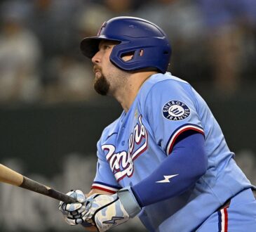 Texas Rangers first baseman Jake Burger follows through and watches the ball in a powder blue uniform.