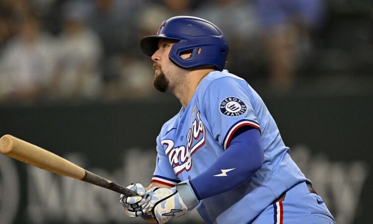 Texas Rangers first baseman Jake Burger follows through and watches the ball in a powder blue uniform.
