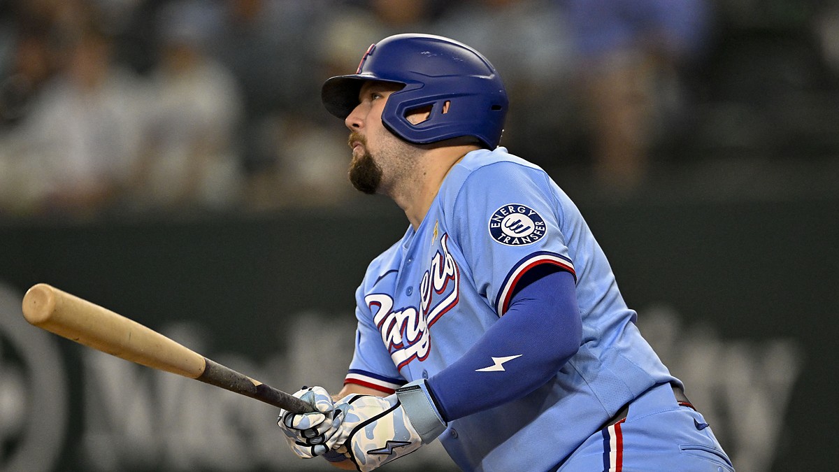 Texas Rangers first baseman Jake Burger follows through and watches the ball in a powder blue uniform.