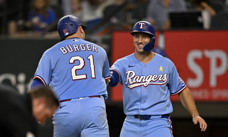 Texas Rangers first baseman Jake Burger and left fielder Wyatt Langford bump fists after Burger's second home run.