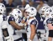 Cowboys tight end Jake Ferguson smiles as teammates crowd around him to celebrate a touchdown.