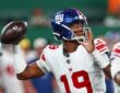 New York Giants quarterback Jameis Winston, No. 19, cocks the ball to throw with a rusher closing.