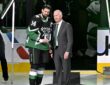 Dallas Stars general manager Jim Nill and captain Jamie Benn hold a commemorative plaque on the ice.