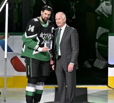 Dallas Stars general manager Jim Nill and captain Jamie Benn hold a commemorative plaque on the ice.
