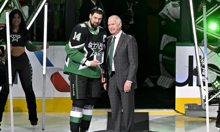 Dallas Stars general manager Jim Nill and captain Jamie Benn hold a commemorative plaque on the ice.