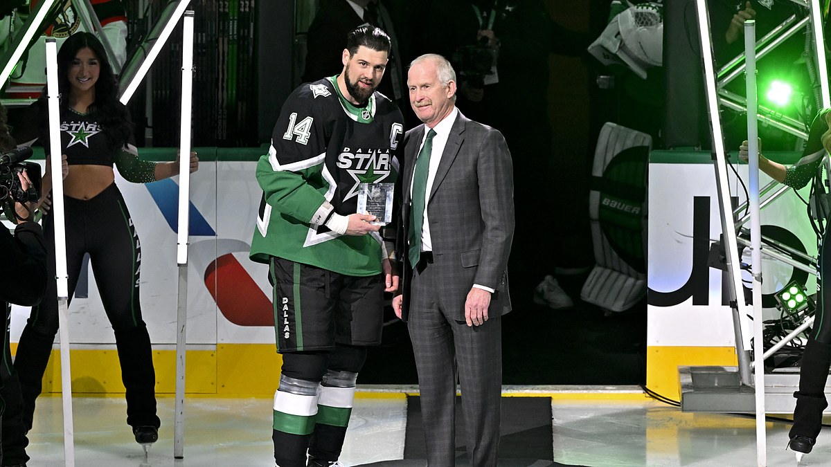 Dallas Stars general manager Jim Nill and captain Jamie Benn hold a commemorative plaque on the ice.