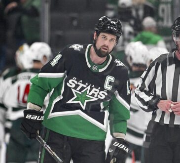 Stars captain Jamie Benn skates off the ice as Minnesota players celebrate behind him.