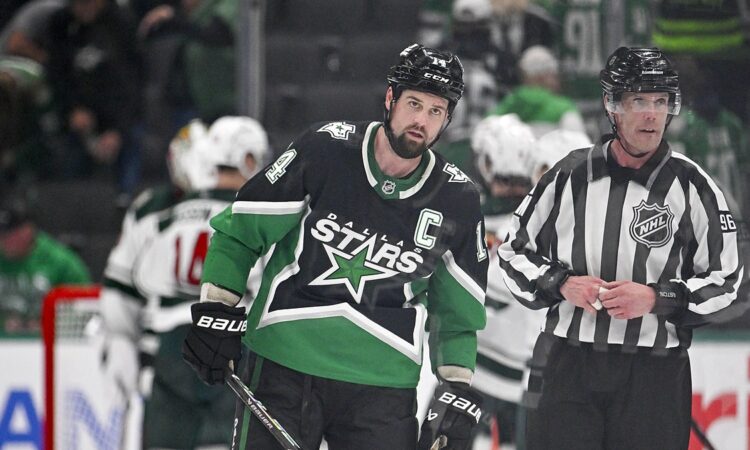 Stars captain Jamie Benn skates off the ice as Minnesota players celebrate behind him.