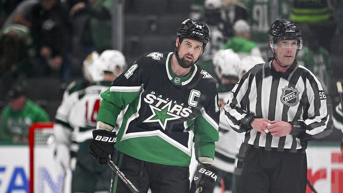 Stars captain Jamie Benn skates off the ice as Minnesota players celebrate behind him.
