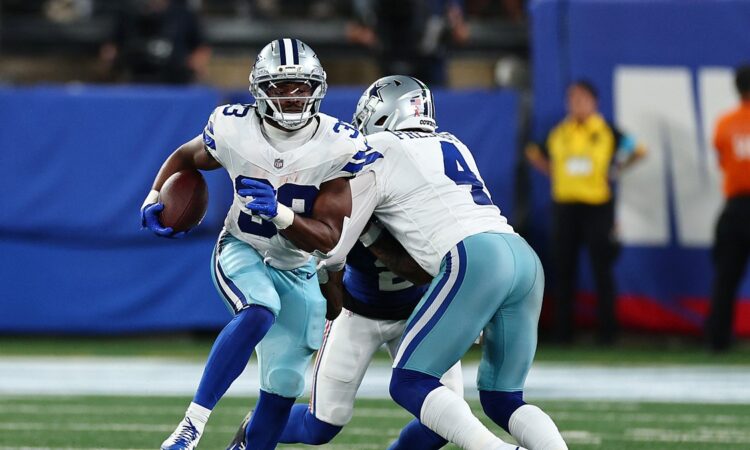 Cowboys running back Javonte Williams cuts upfield with the ball as a teammate blocks a Giants defender.