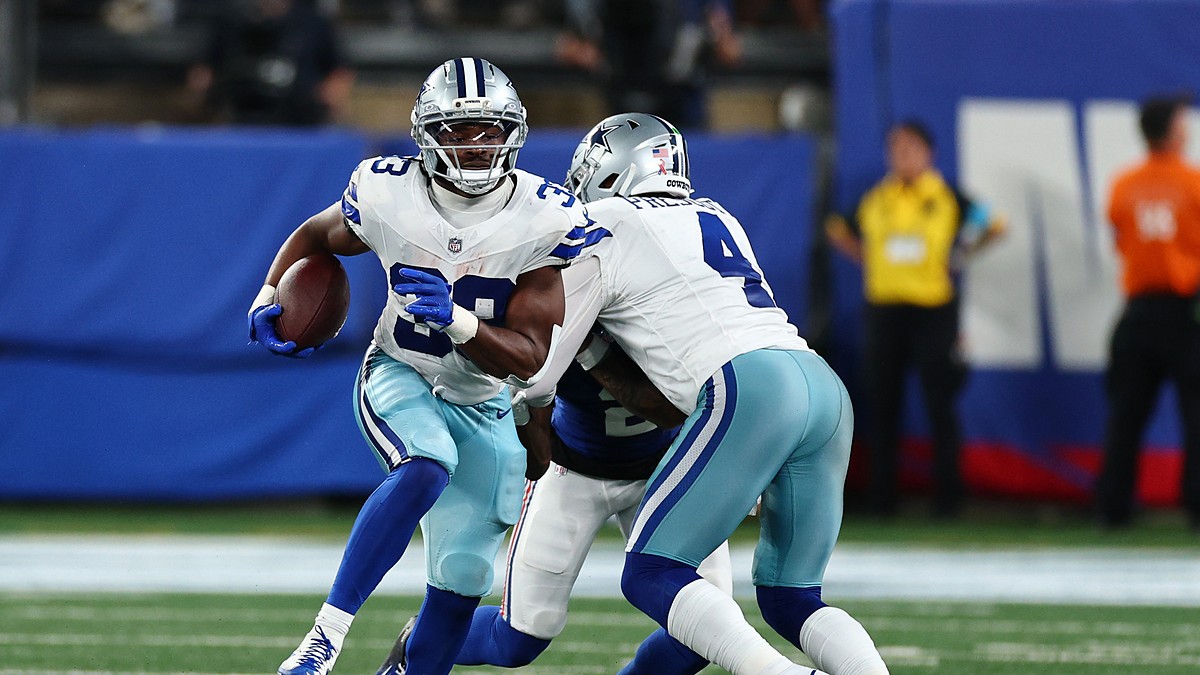 Cowboys running back Javonte Williams cuts upfield with the ball as a teammate blocks a Giants defender.