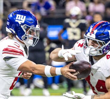 New York Giants quarterback Jaxson Dart extends the ball into running back Cam Skattebo's arms at the handoff.