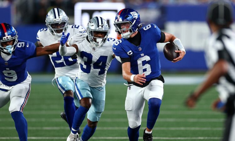Giants quarterback Jaxson Dart scrambles upfield with the ball as Cowboys safety Jalen Thompson pursues.