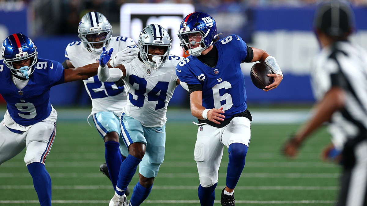 Giants quarterback Jaxson Dart scrambles upfield with the ball as Cowboys safety Jalen Thompson pursues.