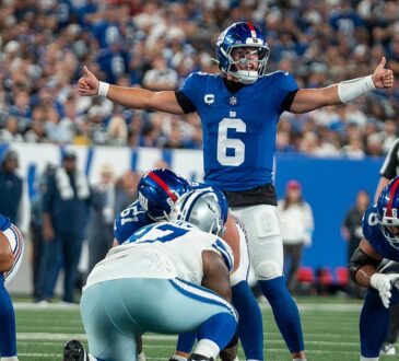 New York Giants quarterback Jaxson Dart spreads his arms to make a call at the line of scrimmage.