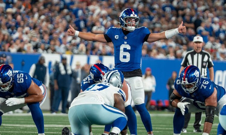 New York Giants quarterback Jaxson Dart spreads his arms to make a call at the line of scrimmage.