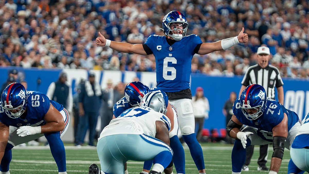 New York Giants quarterback Jaxson Dart spreads his arms to make a call at the line of scrimmage.