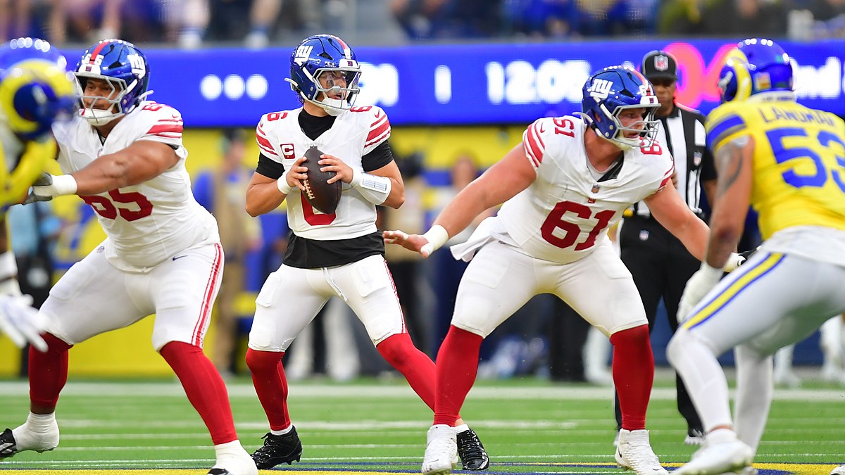 New York Giants quarterback Jaxson Dart holds the ball in the pocket as two offensive linemen block in front of him.