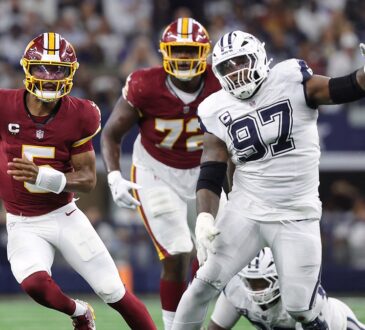 Washington Commanders quarterback Jayden Daniels scrambles with the ball as Cowboys defensive tackle Kenneth Clark closes in.