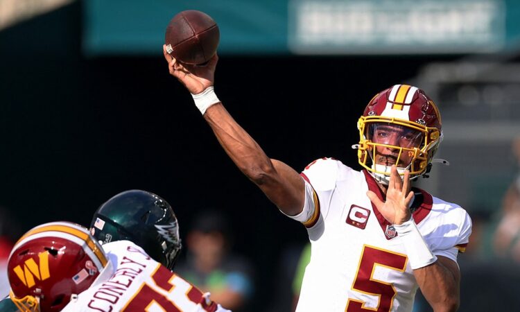 Commanders quarterback Jayden Daniels releases a pass over a lineman as an Eagles defender closes.