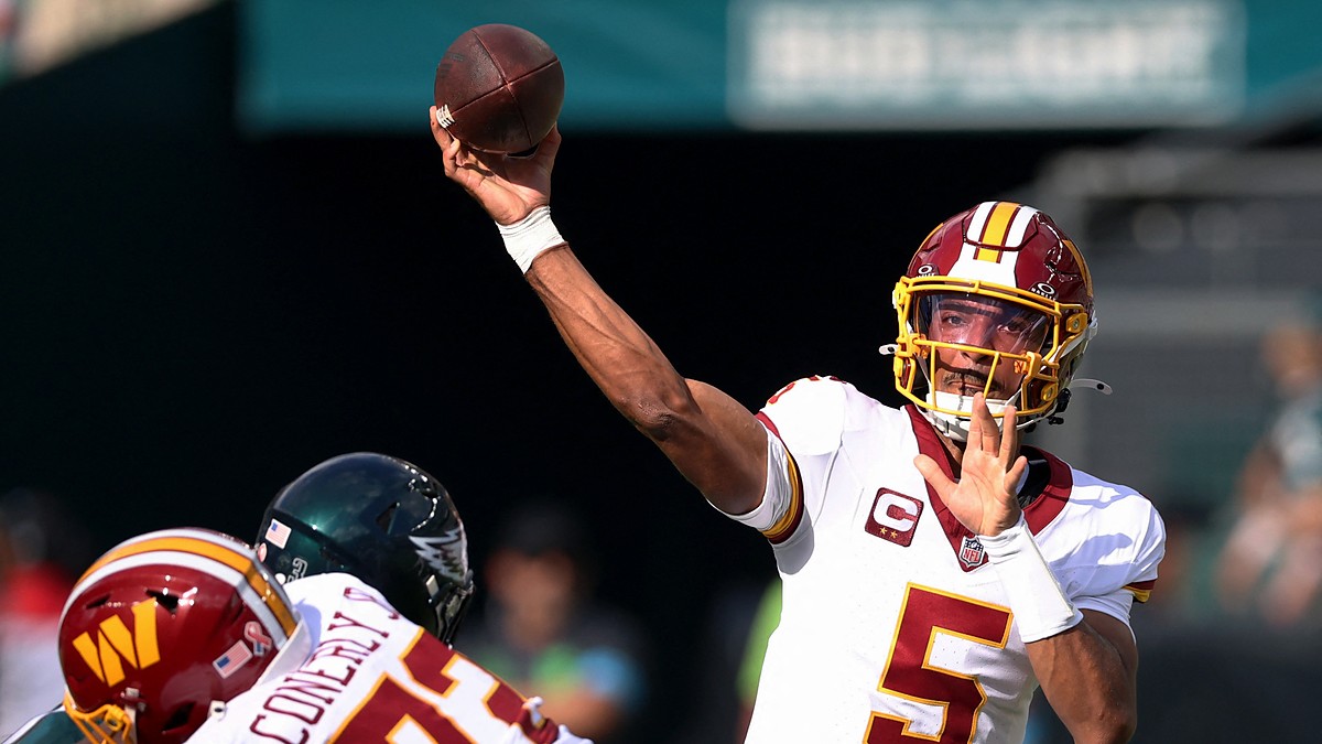 Commanders quarterback Jayden Daniels releases a pass over a lineman as an Eagles defender closes.