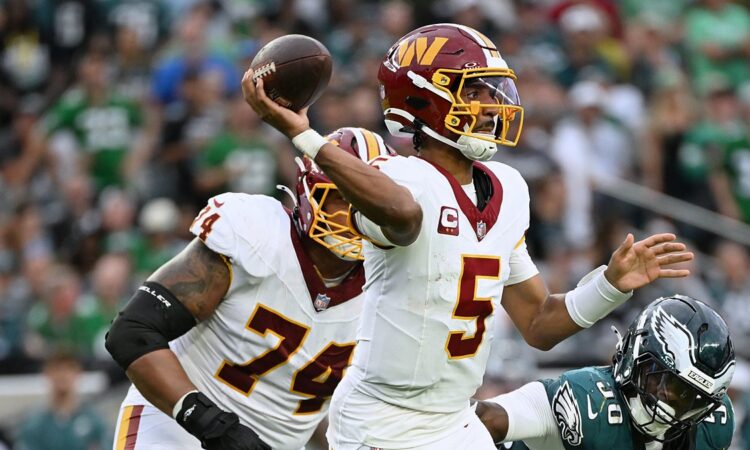Commanders quarterback Jayden Daniels sets and releases a pass as an Eagles defender closes in from his right.