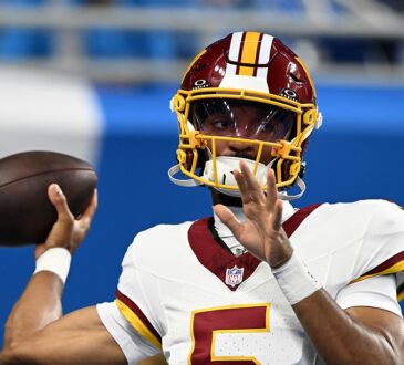 Commanders quarterback Jayden Daniels sets to throw during pregame warmups in a throwback helmet.