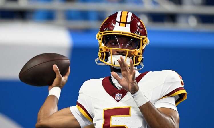 Commanders quarterback Jayden Daniels sets to throw during pregame warmups in a throwback helmet.