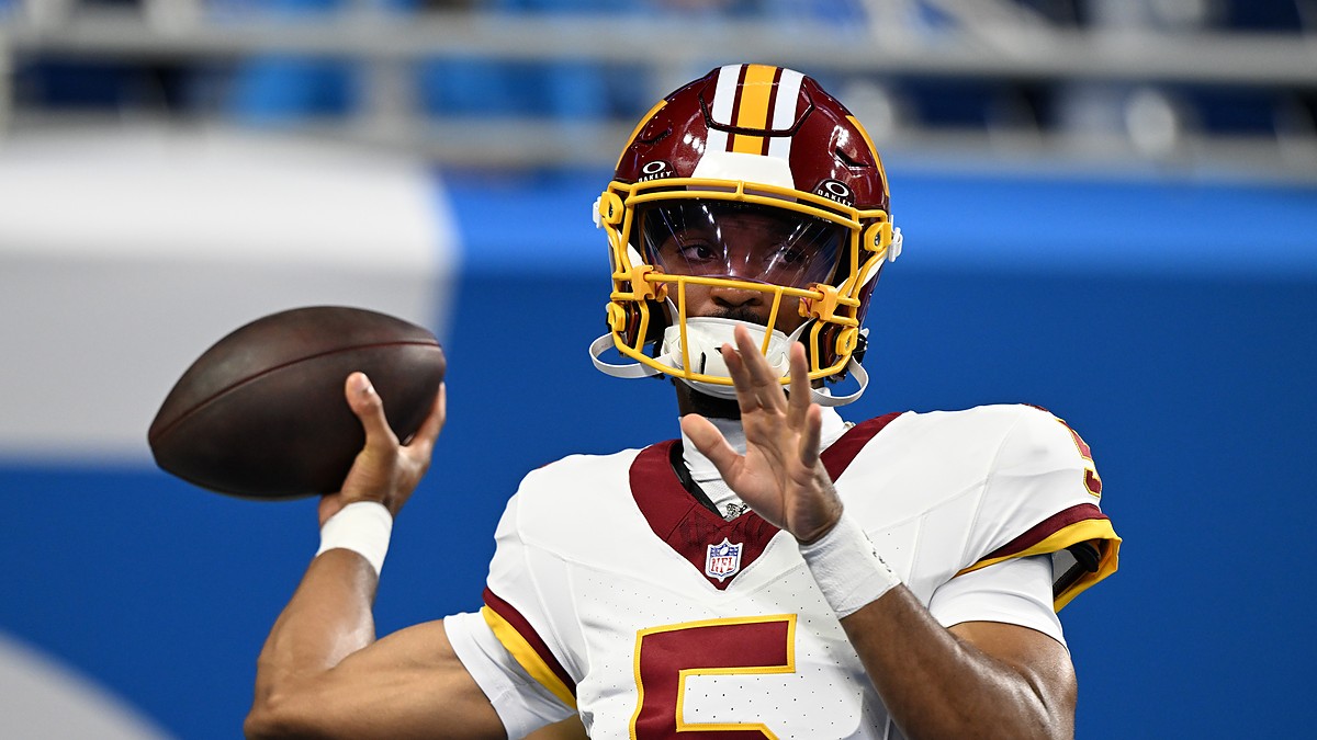 Commanders quarterback Jayden Daniels sets to throw during pregame warmups in a throwback helmet.