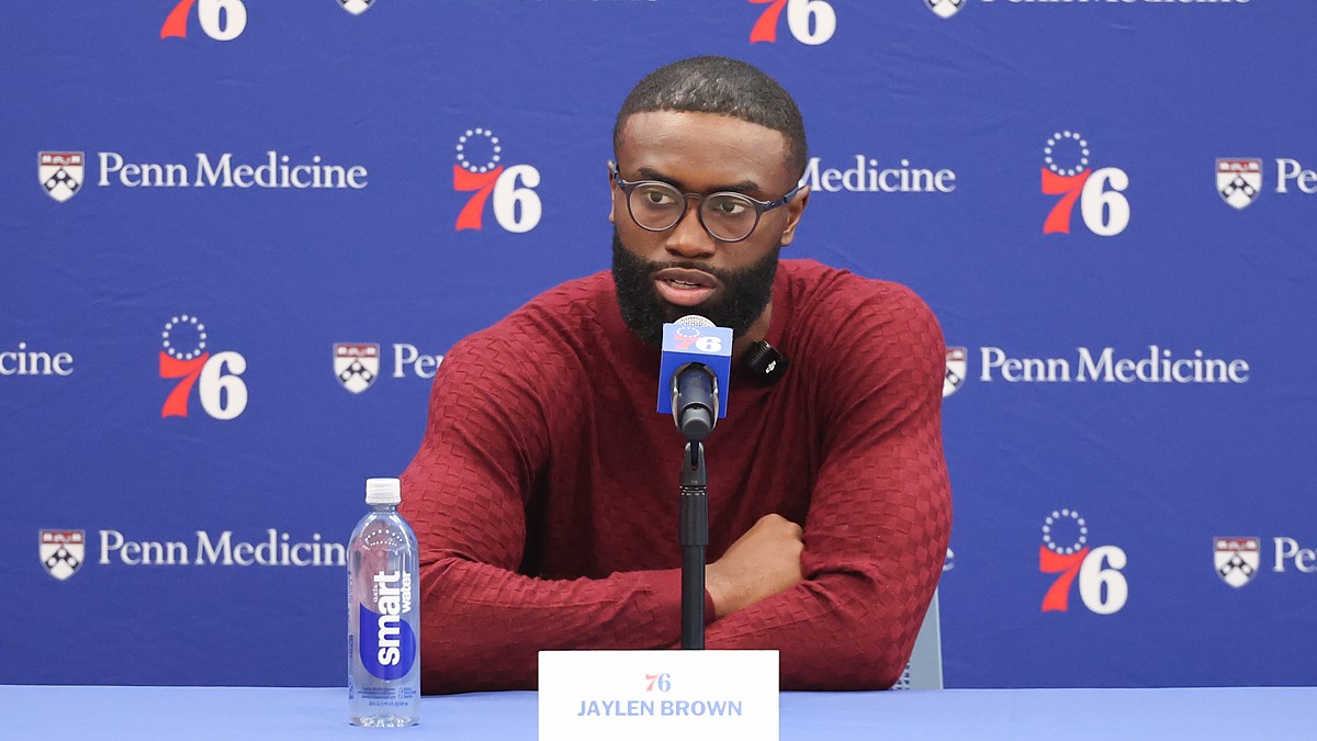 Philadelphia 76ers guard Jaylen Brown speaks at a table with a 76ers microphone and a nameplate reading Jaylen Brown.