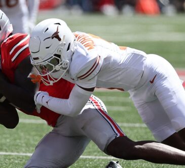 Ohio State Buckeyes wide receiver Jeremiah Smith secures the ball as Texas defensive back Malik Muhammad drags him down.
