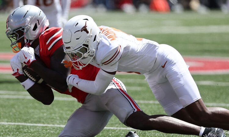 Ohio State Buckeyes wide receiver Jeremiah Smith secures the ball as Texas defensive back Malik Muhammad drags him down.